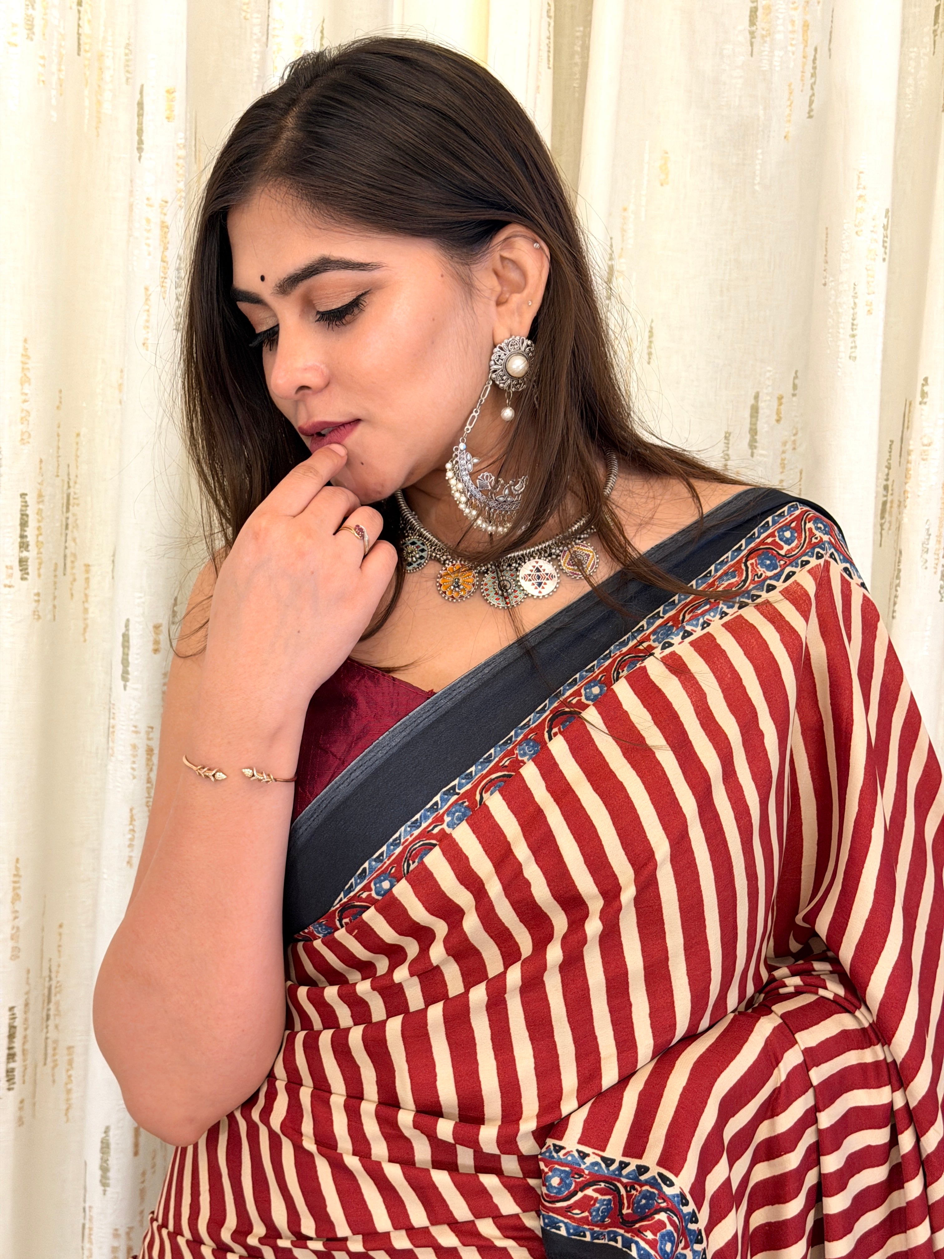 Close-up of maroon striped saree pallu border with silver jewellery