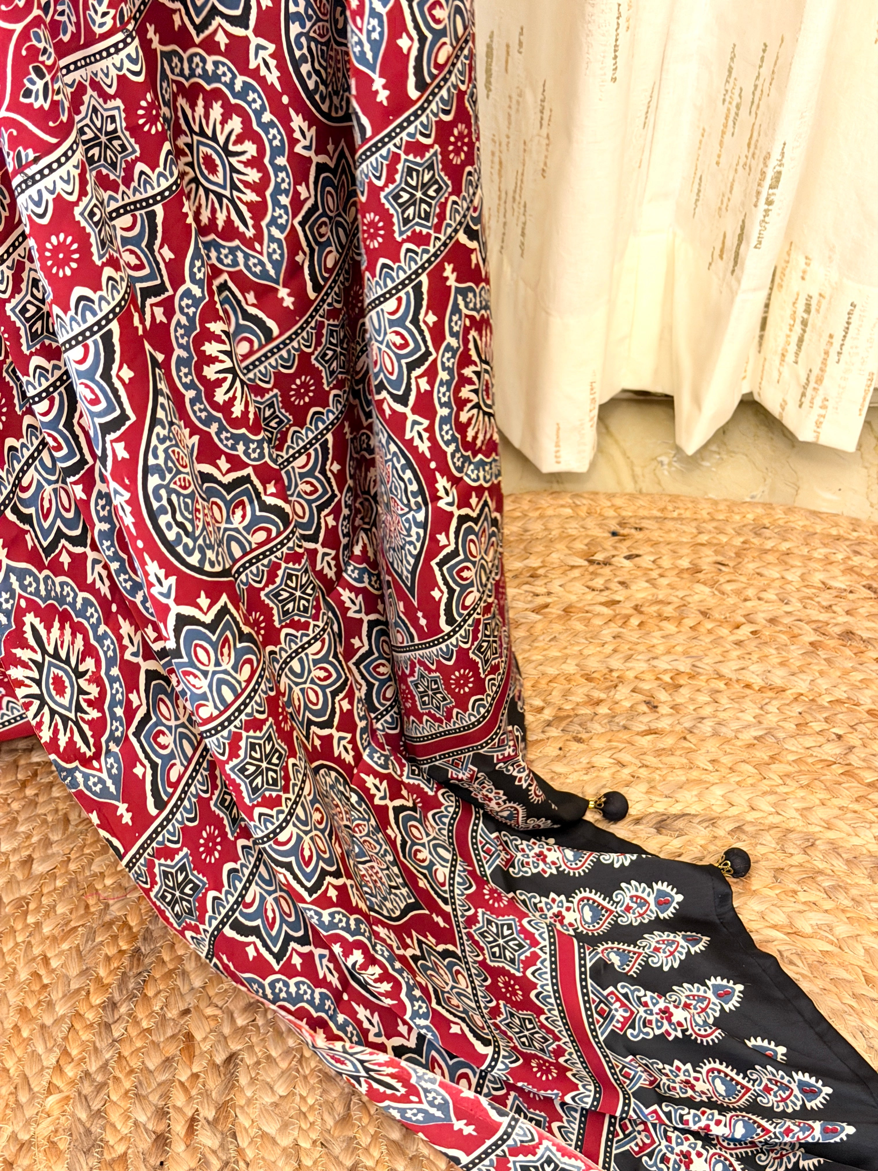 Close-up of maroon Ajrakh medallion pallu with tasseled pom-pom edge