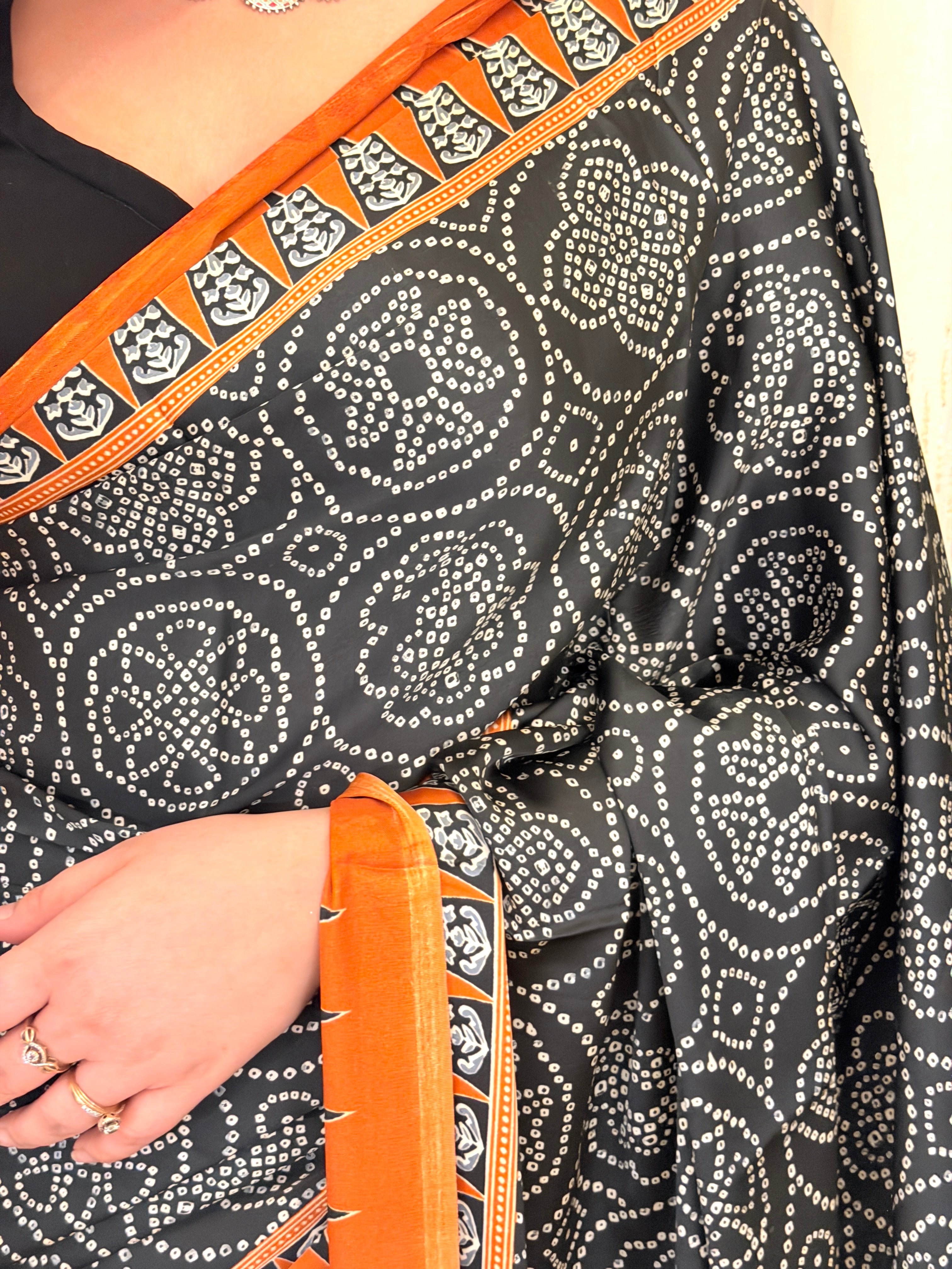 Close-up of black bandhani mandala print with rust temple border on saree