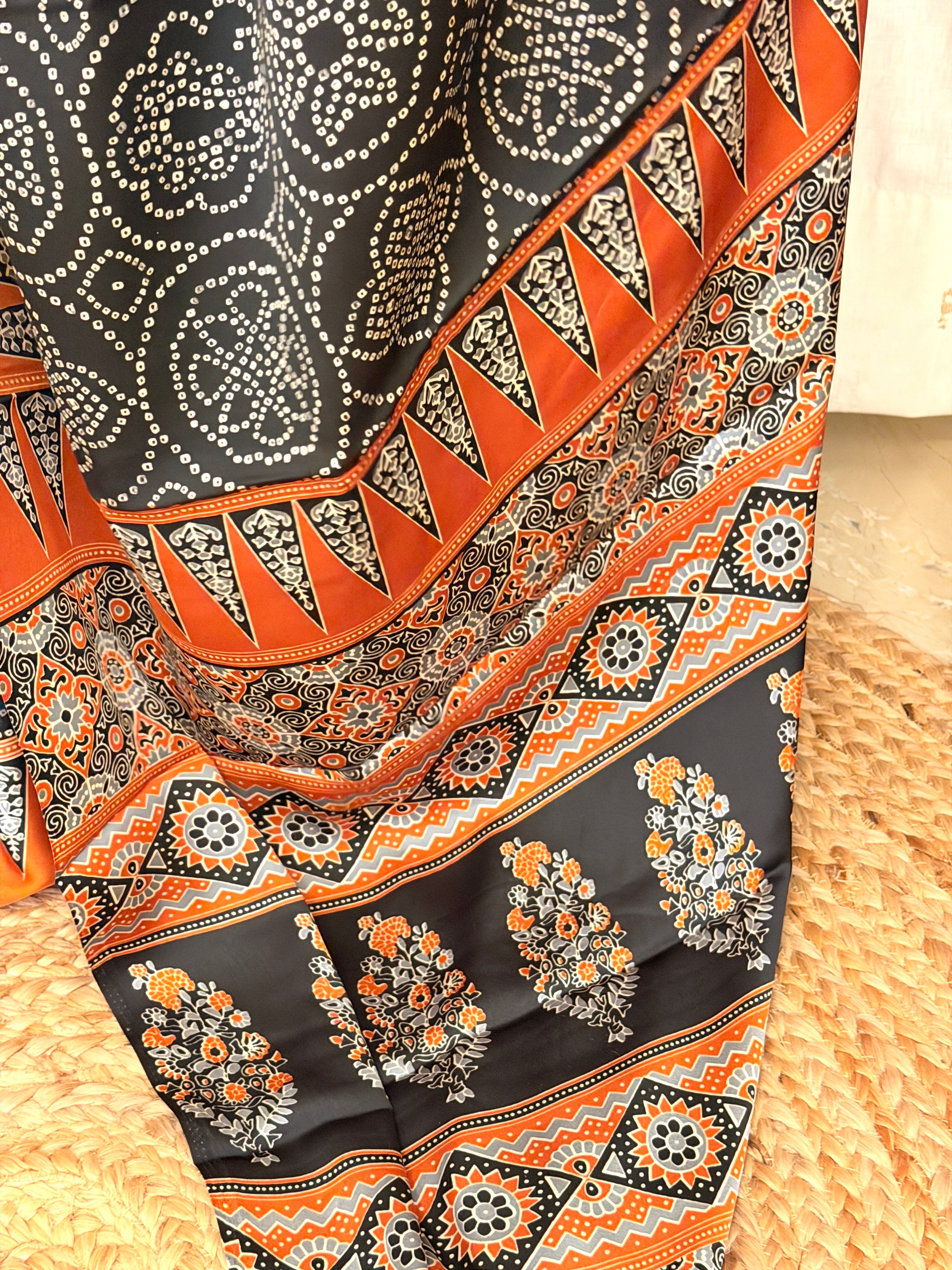 Detailed view of Ajrakh floral and geometric pallu pattern in rust, black and grey