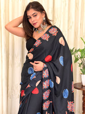 Close-up mid-shot of the black crepe designer saree showcasing the drape, colorful abstract circular prints, and detailed ethnic borders.