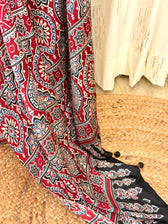 Close-up of maroon Ajrakh medallion pallu with tasseled pom-pom edge