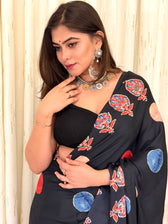 Detailed close-up of the black crepe saree's pallu showing the red and blue leaf-like Kalamkari patterns paired with statement silver oxidized jewelry.