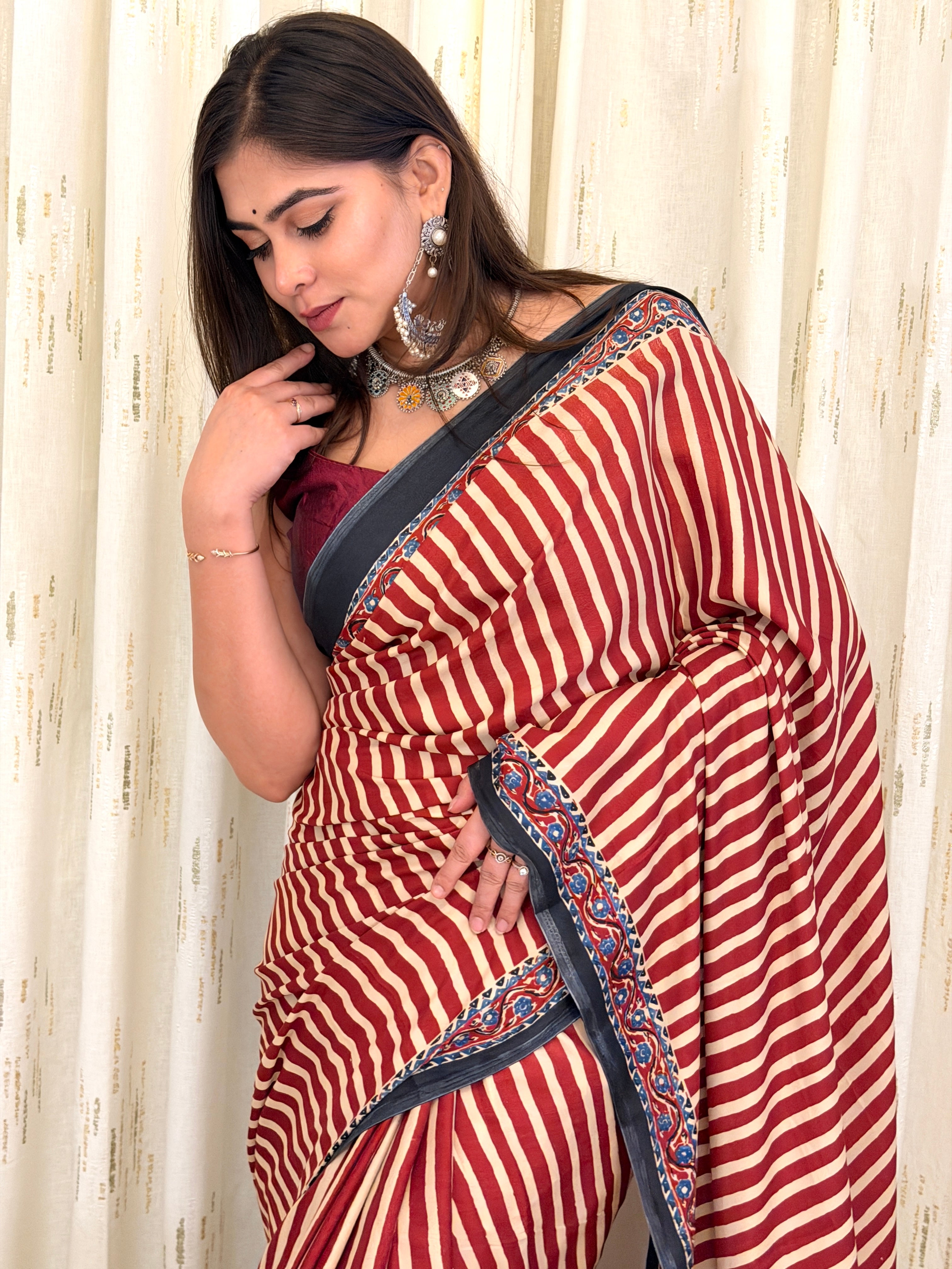 Woman in maroon striped saree with black border - side pose with jewellery