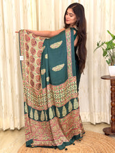 Bottle green Ajrakh leaf print modal silk saree pallu held open by model