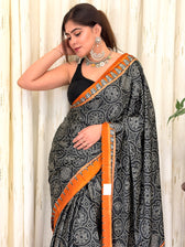 Woman draped in black and rust bandhani saree with silver jewellery - side pose