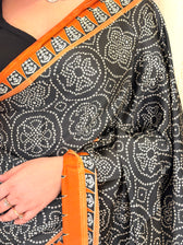 Close-up of black bandhani mandala print with rust temple border on saree