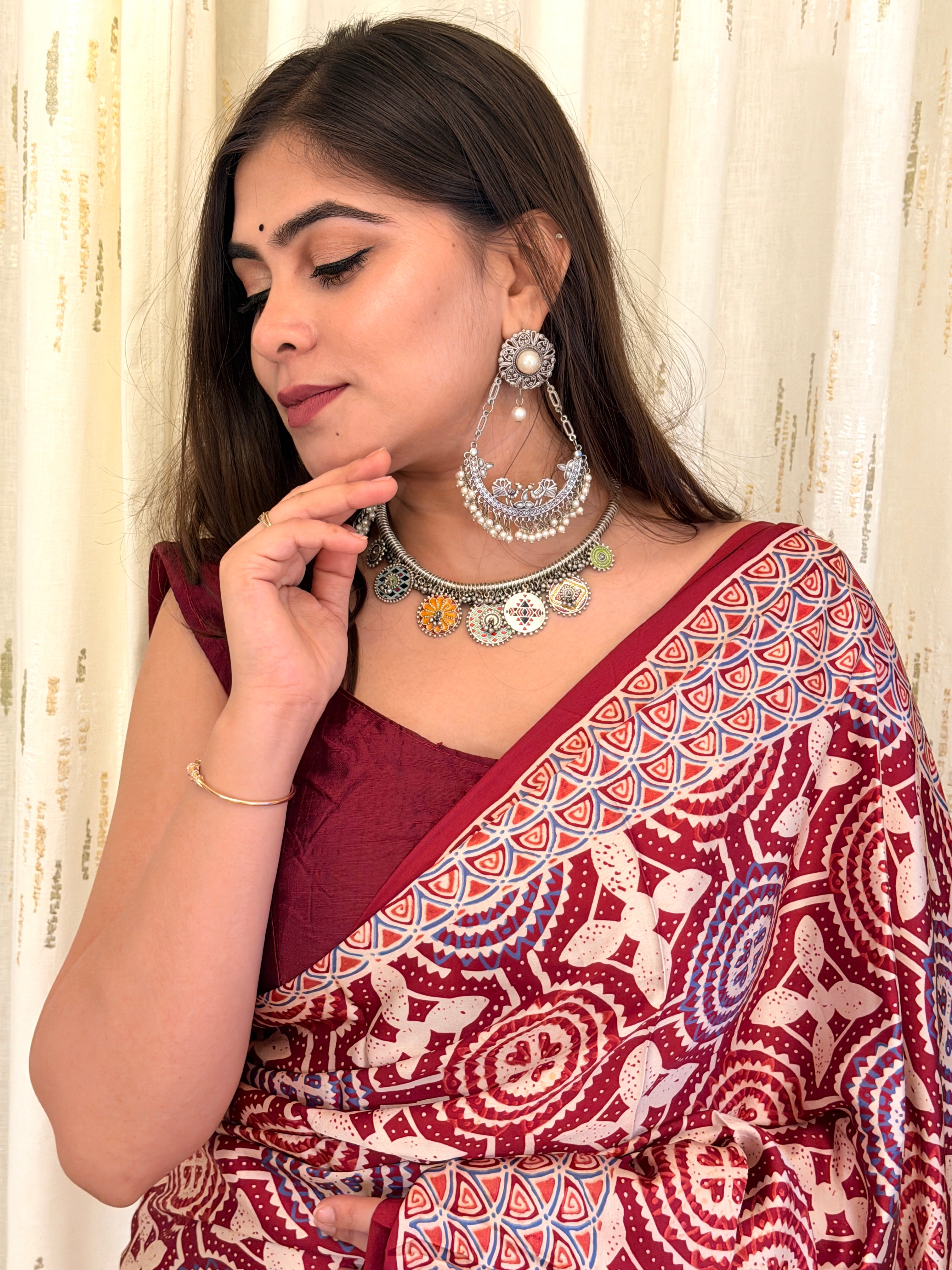 Close-up of maroon Ajrakh saree pallu border near shoulder with silver jewellery