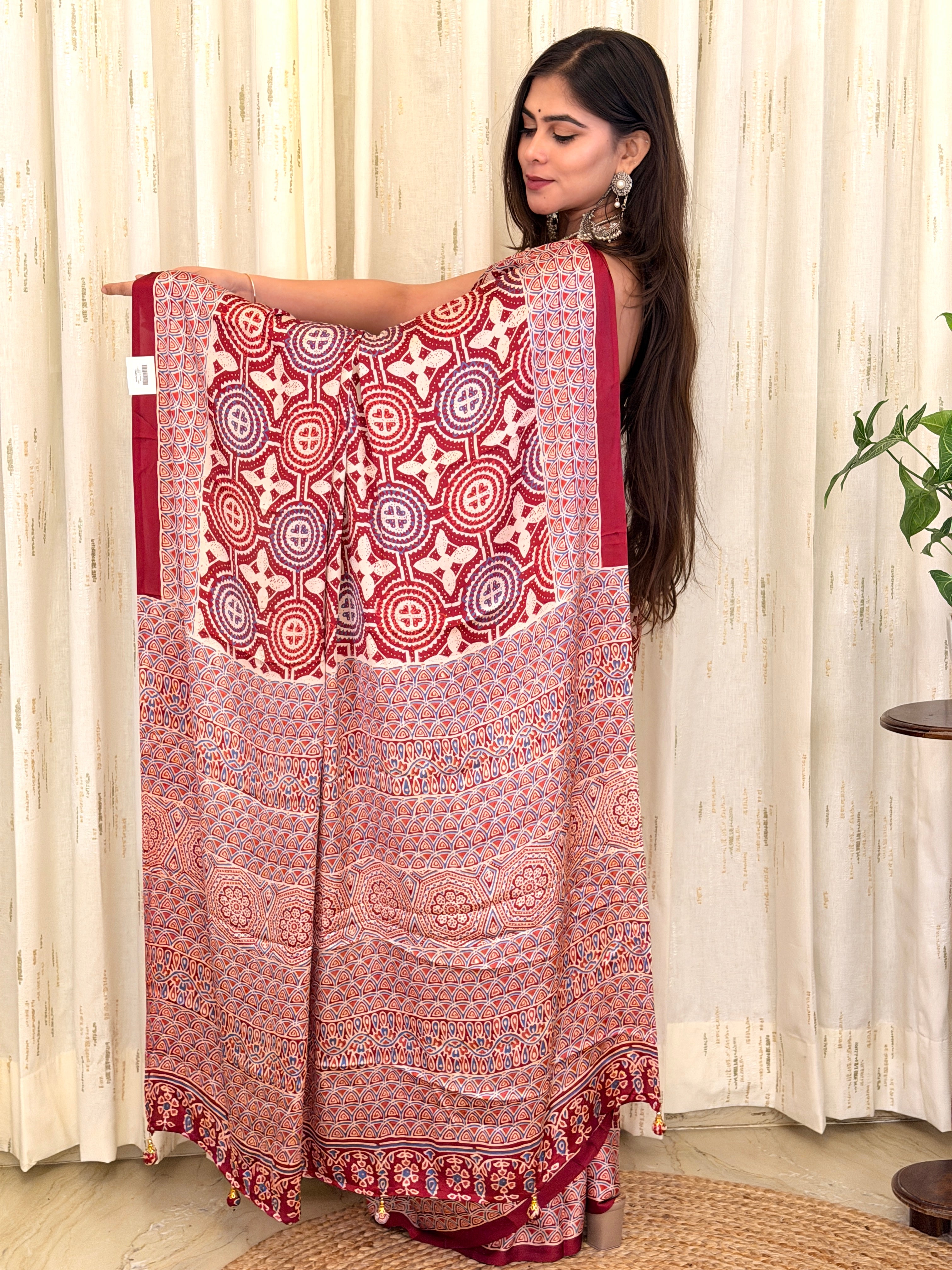 Maroon Ajrakh geometric print modal silk saree pallu held open by model
