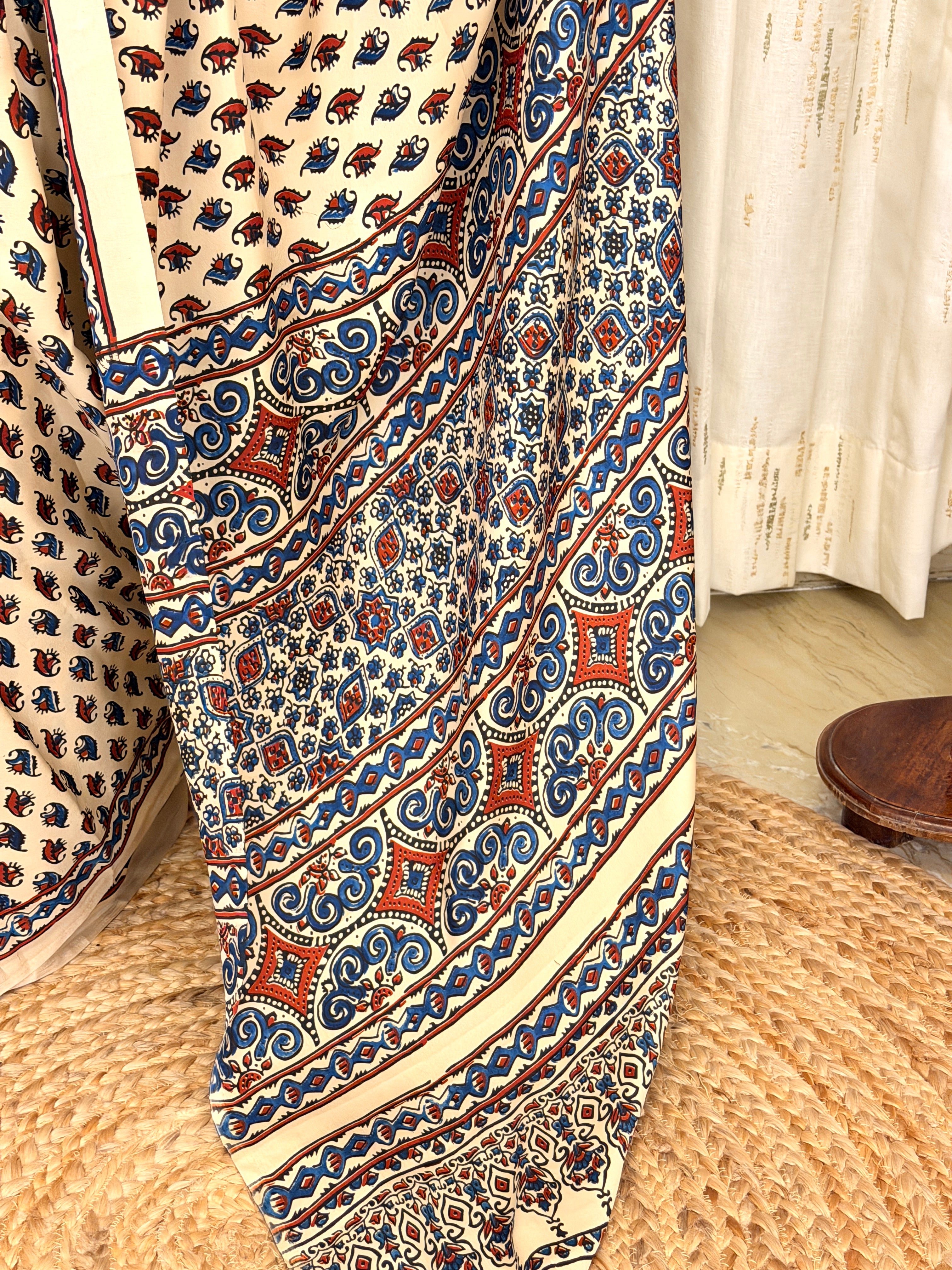 Detailed view of rust and blue Ajrakh scroll pallu border on ivory saree